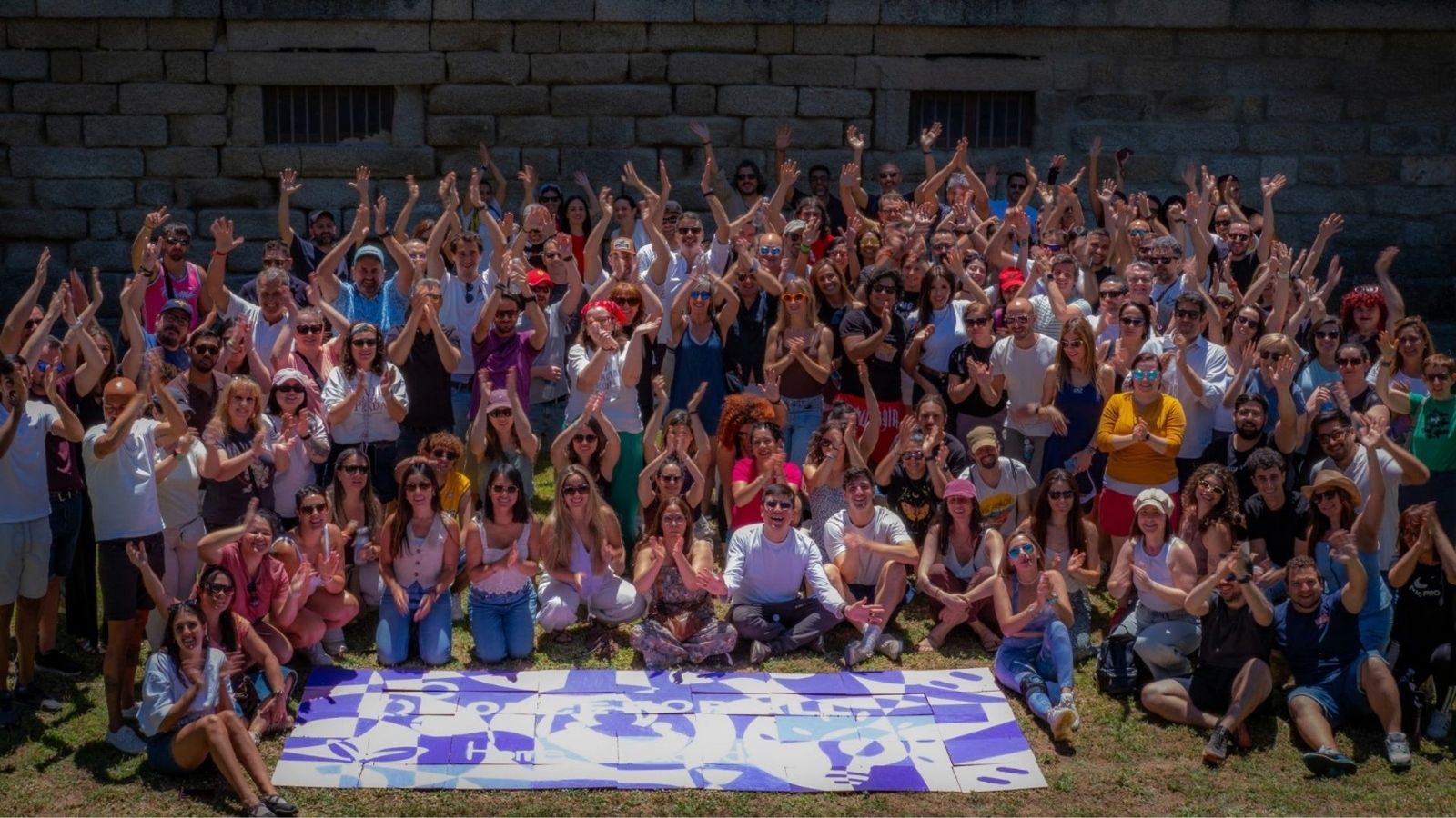 Gran grupo posando alrededor del mural colectivo ya montado